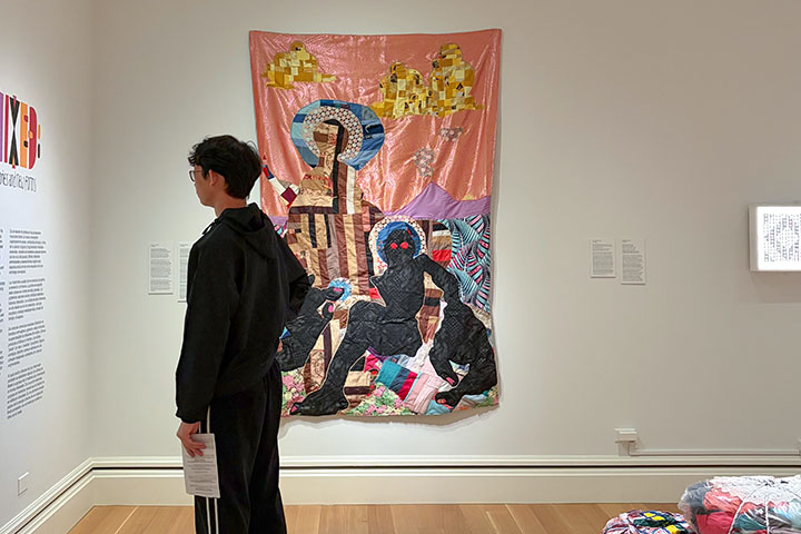 young person reading exhibition description in a gallery of art