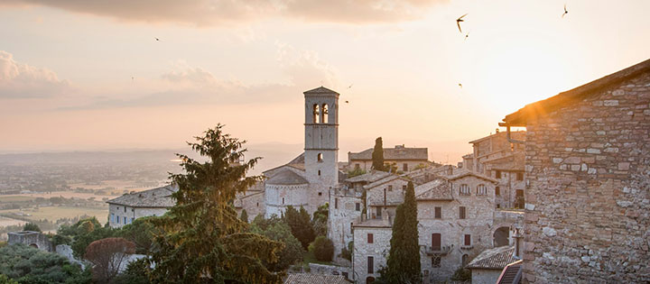 Stone hillside village at sunset with a historic church tower and surrounding landscape