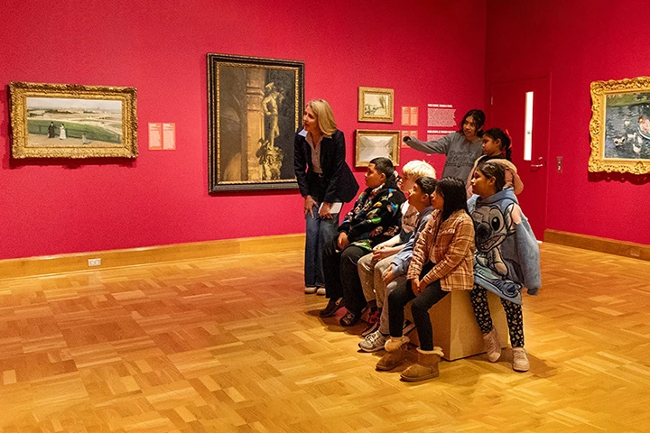 photo of youth group on tour in a museum with red walls and hanging art