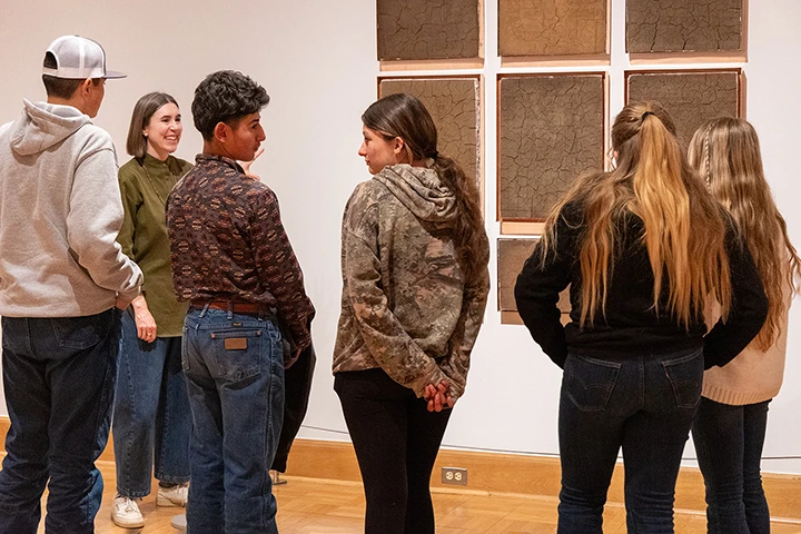 photo of youths on tour of a museum led by an instructor with art on the walls
