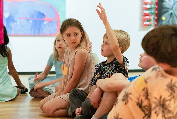 photo of kids in a museum gallery with one of them raising a hand