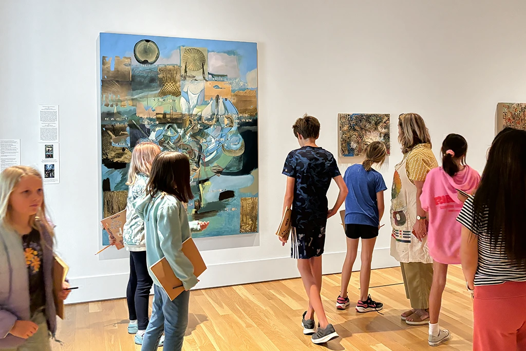 photo of kids in a gallery with notebooks looking at art